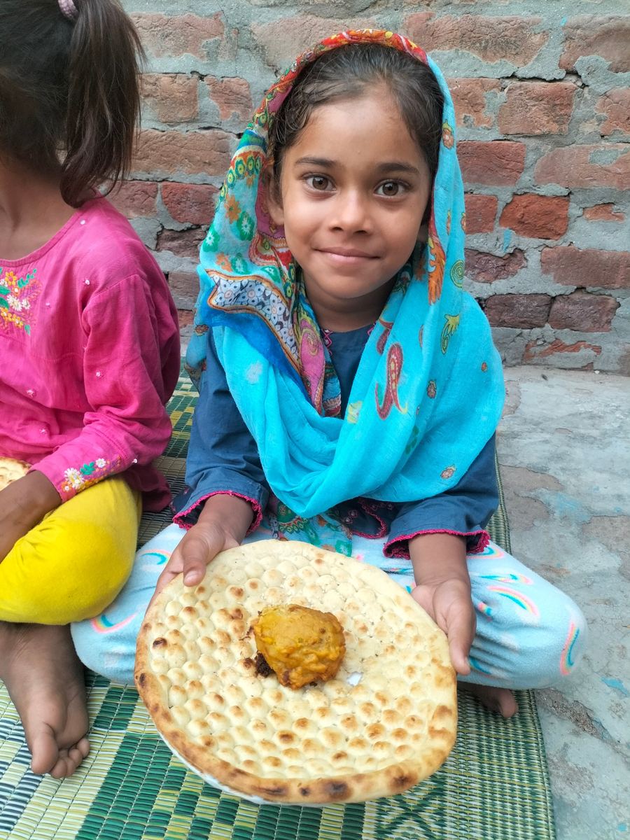 Une fillette souriante tient son pain et son repas
