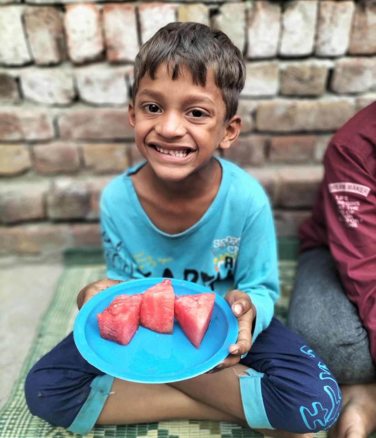 Un garçon souriant avec une assiette de melon d'eau
