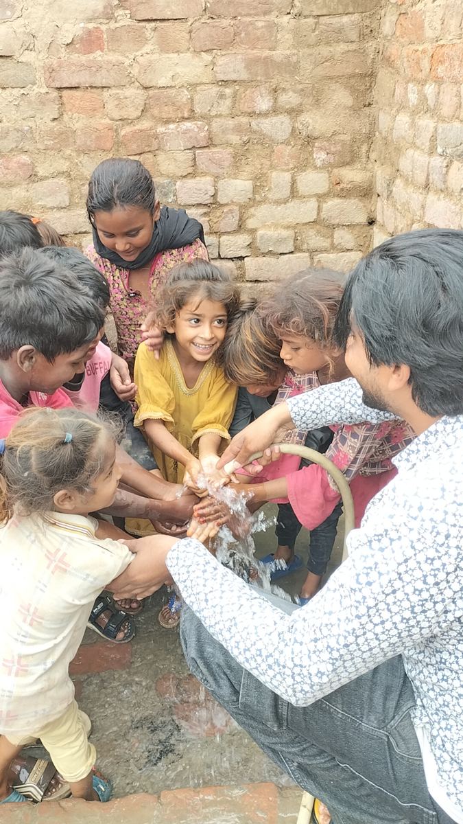 Des enfants joyeux se lavent les mains à l'eau du puits