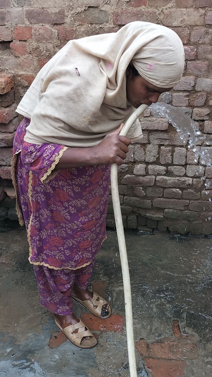 Une femme boit l'eau potable du puits
